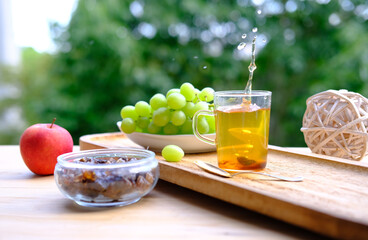 useful herbal green tea in a glass mug, bunch of green grapes, brown sugar, concept of lifestyle, tea on the terrace, seasonal, tea summer mood