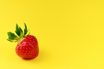 Strawberry red lies in the lower left corner on a yellow background with a copy space