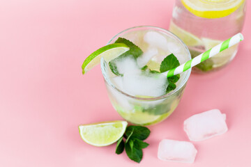 Top view on a carafe with refreshing water with lemon or lime and ice and in the foreground a glass...