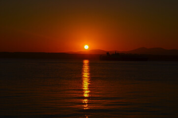 Obraz premium Canakkale with a sunrise and a steamer, morning hours, red colors, sunrise, orange, red, yellow colors 