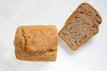 Sliced wheat bread on a linen texture. Fermented whole grain homemade bread.