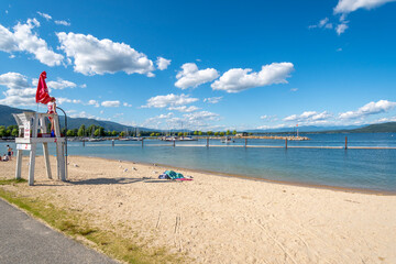 A young female lifeguard stands on duty at a lifeguard station along the sandy city beach of Lake Pend Oreille at Sandpoint, Idaho, in the USA