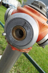Extreme close up of water fire hydrant, green background. Detail of orange grey water fire hydrant