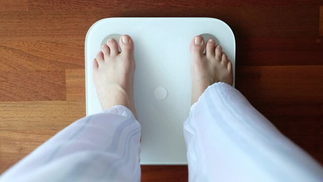 Crop woman standing on digital weight scales