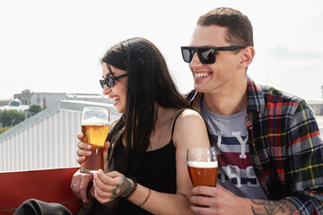 Happy smiling couple toasting and drinking beer at outdoor pub or bar on rooftop at summer, copy space