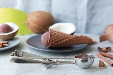 Homemade ice cream in waffle cones, coconuts on the kitchen table by the window, preparing a healthy dessert