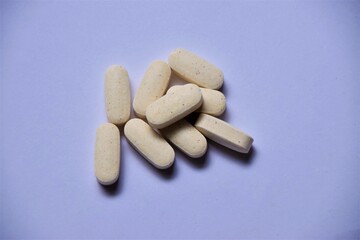 Pile of white vitamin pills on white background with plenty of copy space