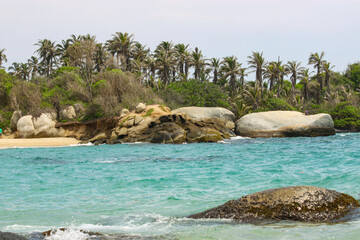 Caribbean sea with white sand beach surrounded by tropical forest in Tayrona National Park in Cabo San Juan del Guia, Colombia.