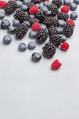 Blueberries, raspberries and blackberries on gray