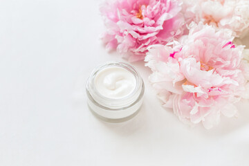 Jar of skin care cream and pink peonies