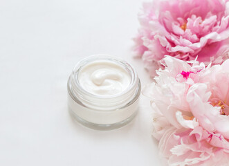 Fototapeta na wymiar Jar of skin care cream and pink peonies