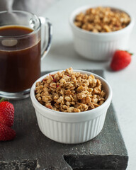 Homemade granola in a white bowl with strawberries and a Cup of coffee. The concept of a healthy Breakfast.