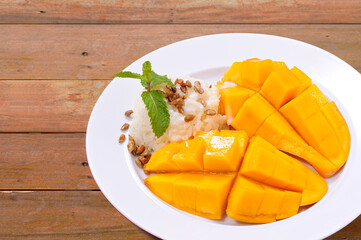 mango and sticky rice pour the coconut milk, topping with sunflower seed on wood background