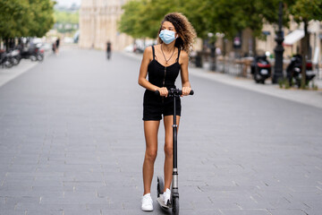 young woman ride scooter the street wearing mask to protect from coronavirus