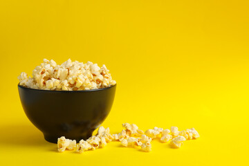 Fototapeta na wymiar Bowl with tasty popcorn on yellow background. Food for watching cinema