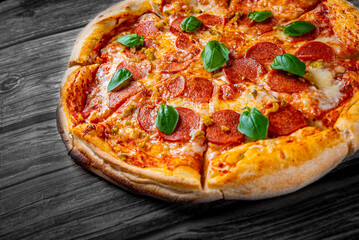 Pepperoni Pizza with Mozzarella cheese, salami, Tomato sauce, pepper, Spices and Fresh basil. Italian pizza on wooden table background