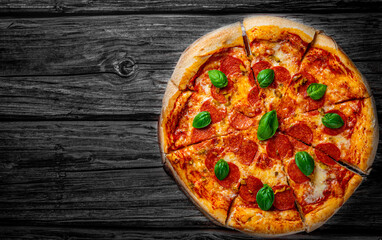 Pepperoni Pizza with Mozzarella cheese, salami, Tomato sauce, pepper, Spices and Fresh basil. Italian pizza on wooden table background