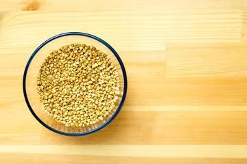 Green buckwheat in a bowl on a wooden table.