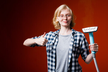 Worker chemical cleaning on a red background. Blonde girl looks at a new steamer to replace the...