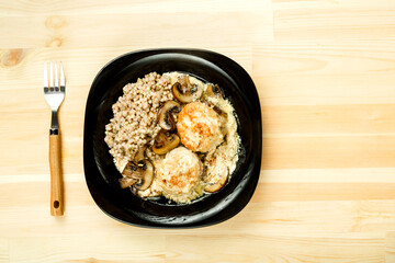 Chicken meatballs with mushrooms in a creamy sauce with a side dish of green buckwheat.
