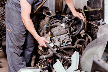 Mechanic looking at the condition of a disassembled car engine.