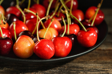 Sweet cherries on a plate on a wooden surface.