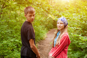 A young couple walks through the woods holding hands