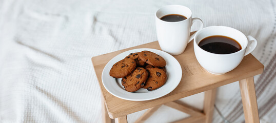 Breakfast in bed. Hot coffee with oatmeal cookies with chocolate on a wooden tray.