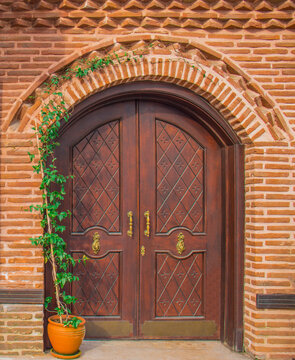 Old vintage wooden door with brick archway. Front door, double brown front door with a secured front entrance.

