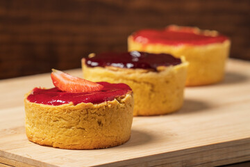 Three mini cheesecake on a wooden cutting board.