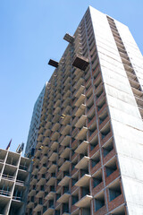 A tall house is built by a contractor with a crane. Photo of the house on a background of blue cloudless sky. Home construction, construction cranes, unfinished house