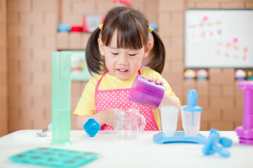 Obraz na płótnie Canvas toddler girl making ice lolly for homeschooling