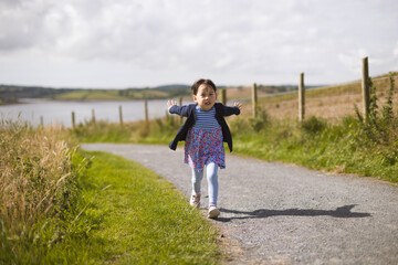 toddler girl running on the summer countryside road