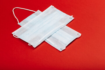 healthcare, medicine and charity concept: cross made from two white surgical masks for protection from COVID-19