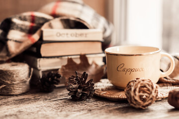 Details of still life on window. Book with scarf and cup of tea on wood background. Autumn mood.