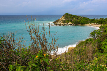 Caribbean sea with white sand beach surrounded by tropical forest in Tayrona National Park in Cabo...