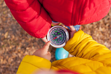Girls Toddler holding compass in the hands. Children exploring nature in the forest on warm autumn day Kids learning how to use compass. Outdoor recreation and awesome adventures with children in fall © tgordievskaya