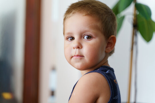 Portrait of small caucasian boy at home - little child two years old male standing in room looking to the camera serious in day - childhood growing up concept