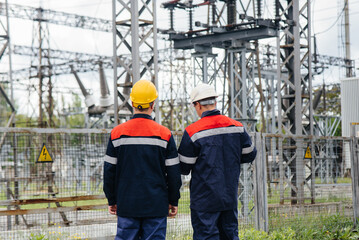Two specialist electrical substation engineers inspect modern high-voltage equipment. Energy....