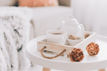 Cup of hot drink and teapot on a serving tray on table. Cozy autumn or winter concept.