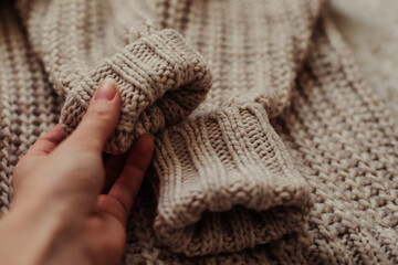 Fototapeta na wymiar Female hand touches a warm and soft sweater.