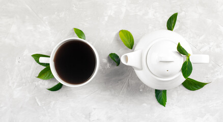 Herbal tea, cups and teapot with leaves on grey concrete background. Flat lay.