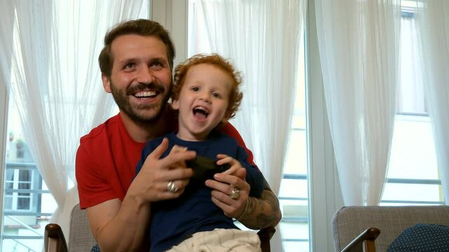 Father and son playing video game at home