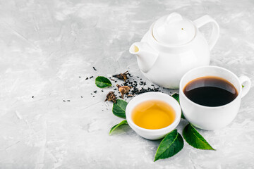 Herbal tea, cups and teapot with leaves on grey concrete background. Flat lay.