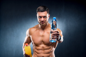 Fototapeta na wymiar Sexy sportsman holding a bottle of water and soda. Choosing between healthy and harmful drink. Portrait. Closeup