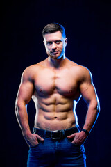 Fototapeta na wymiar Closeup of a handsome power athletic man bodybuilder. Fitness muscular body on dark background. Closeup