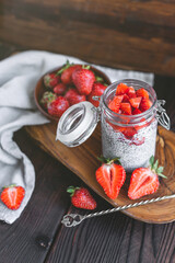 chia pudding with strawberry sauce, fresh berries and milk on rusic background