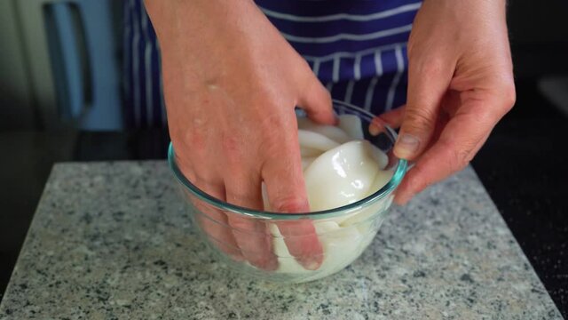 squid carcasses, a chef mixes with hand the raw calamari in a glass bowl,closeup