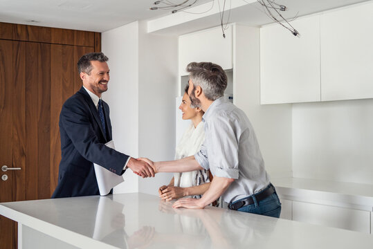 Real estate agent greeting couple
