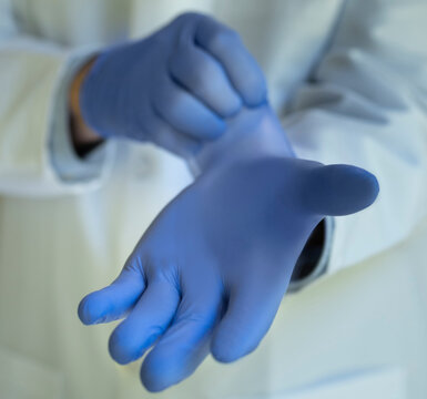 Close-up&not;&dagger;of doctor putting on blue latex gloves